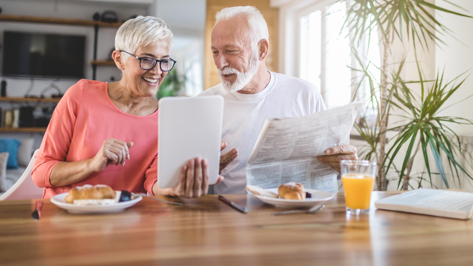 Älteres Paar mit Zeitung und Tablet in der Hand